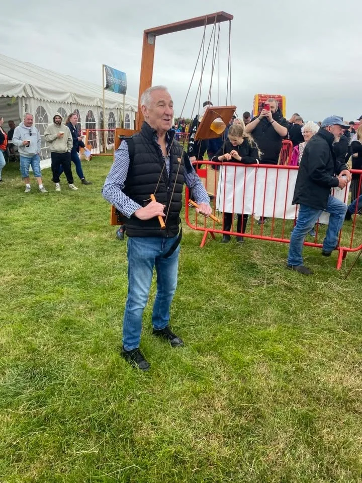 A man wearing a Beer Puppeteer frame at a busy show field