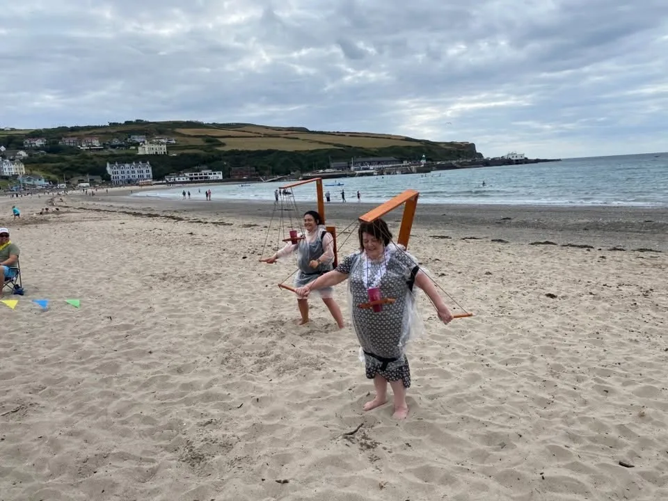 Two people using Beer Puppeteer frames on Port Erin beach
